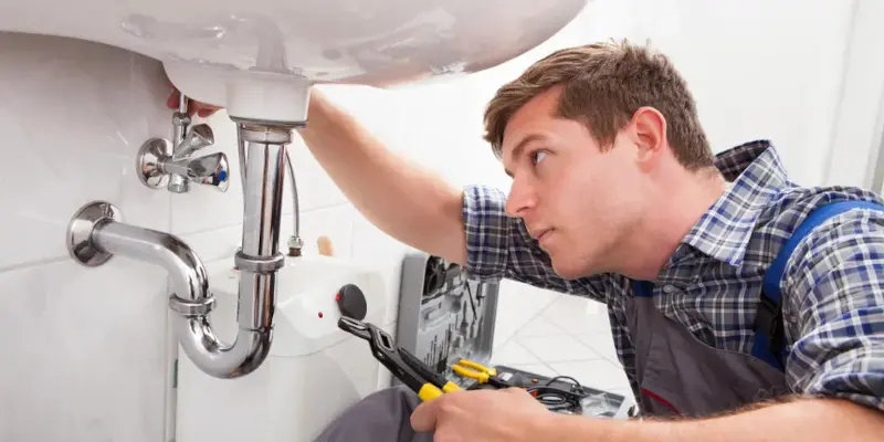 Plumber inspecting lines under a residential sink